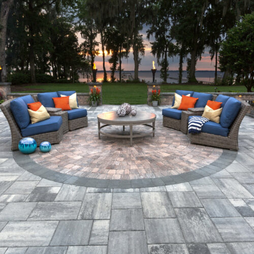 Custom Patio with circle design of red brick in the middle and retains wall with torches