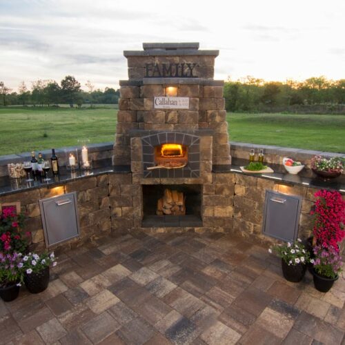 Outdoor pizza oven with stainless steel appliances and wood storage