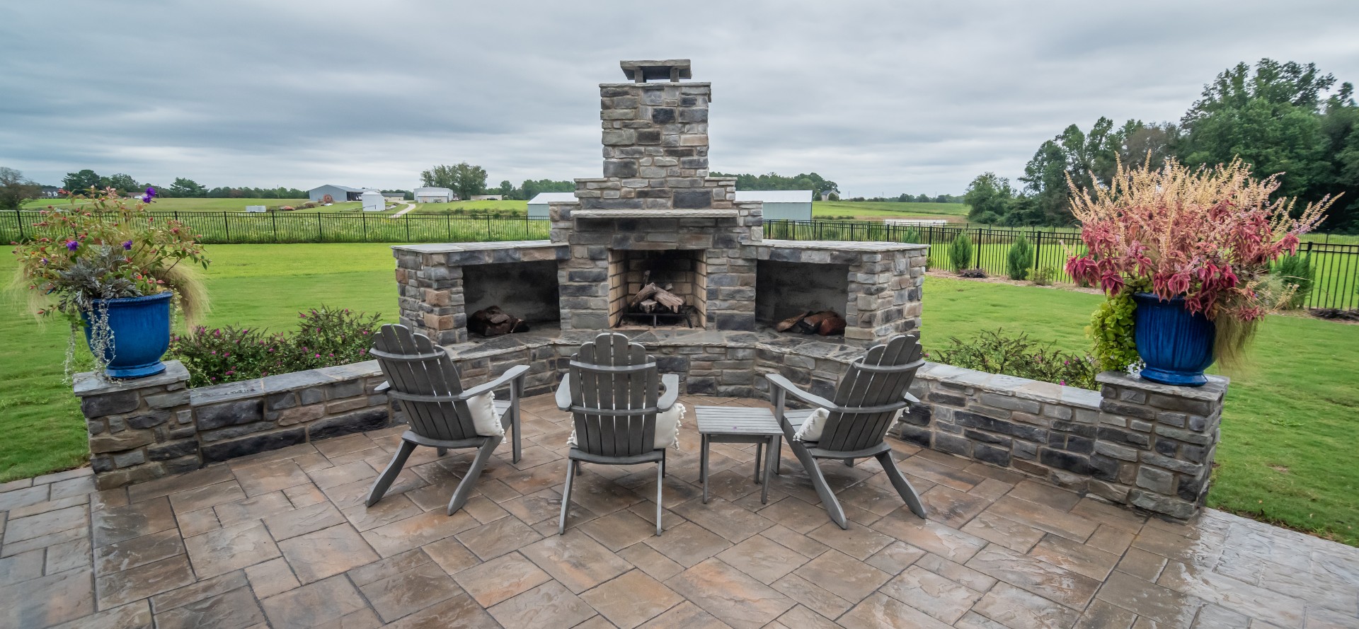 Outdoor living space with stone fireplace, retaining wall and custom paver patio