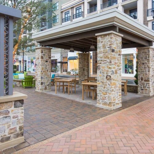 Custom brick pathway with stone pillars for a covered seating area