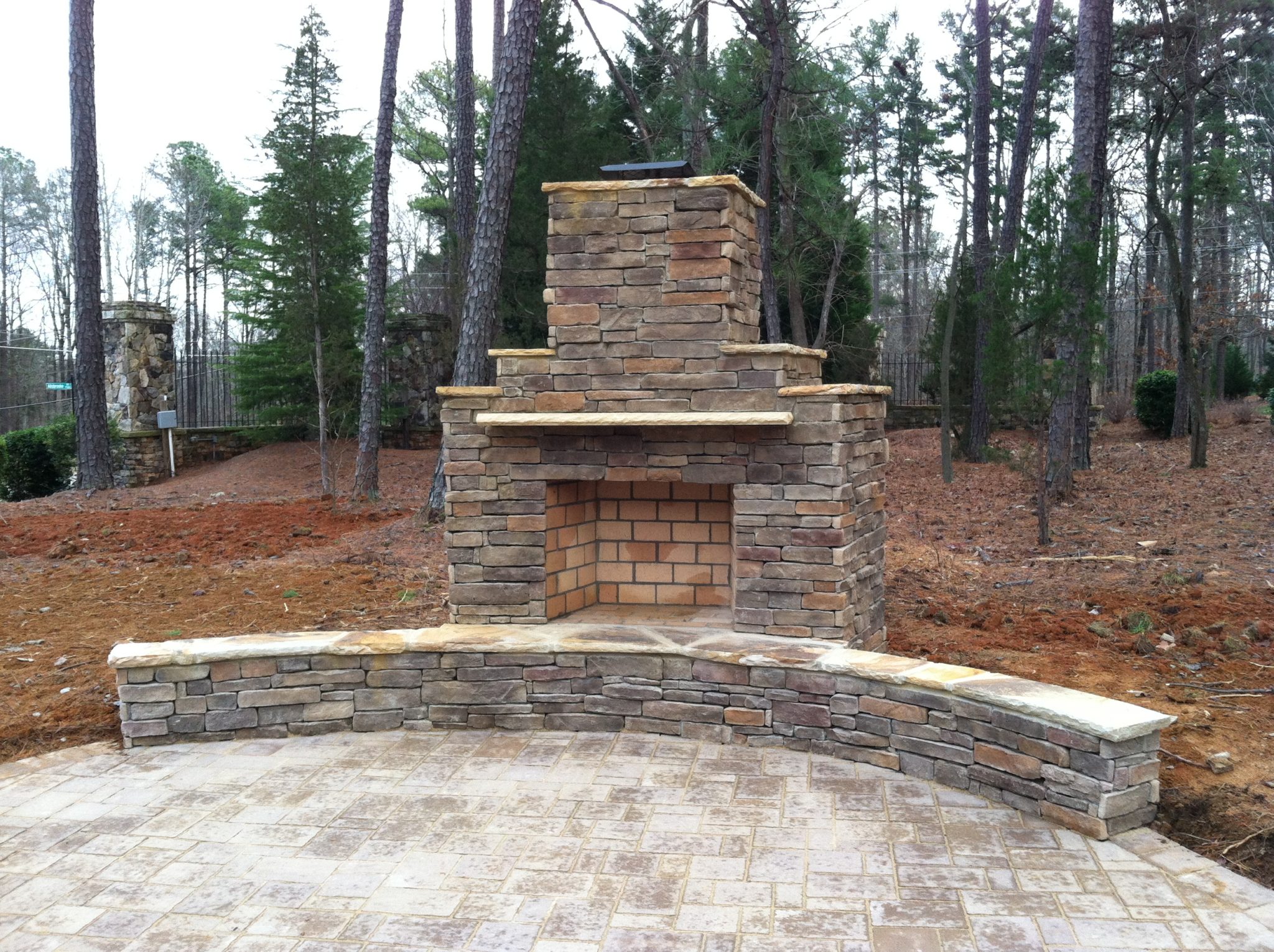 Outdoor living space with stone fireplace, retaining wall and custom paver patio