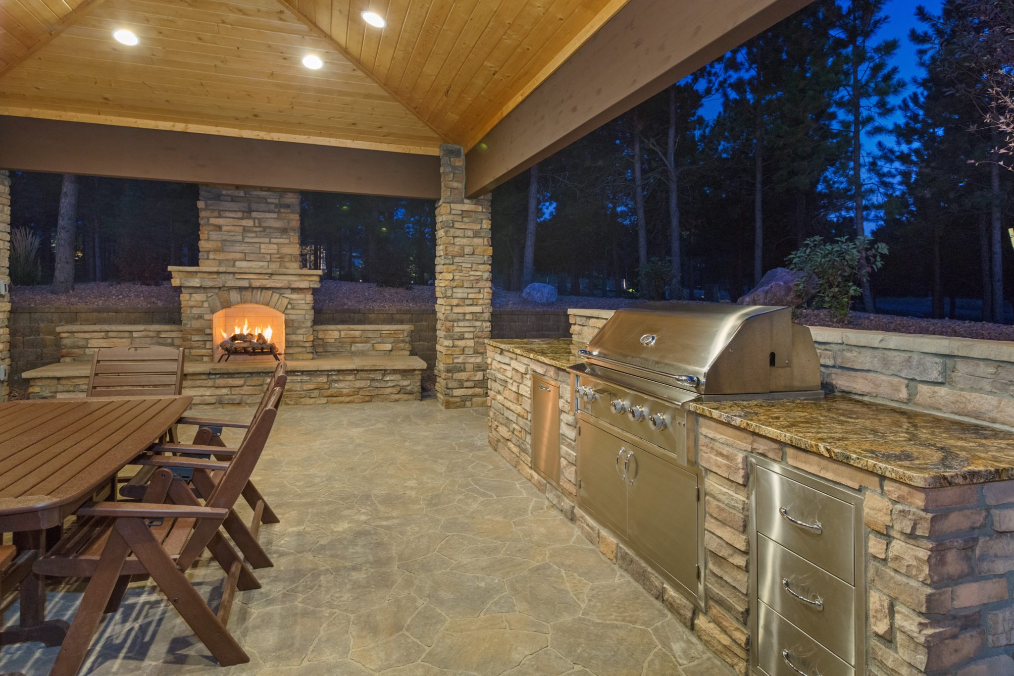 Outdoor living space with stone fireplace, retaining wall, outdoor kitchen and custom paver patio