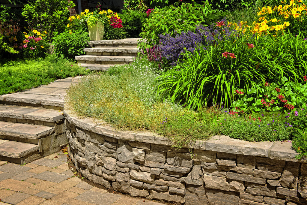 Stone Veneer Retaining Wall Supporting a beautiful Flower Garden, and Custom Stone Staircase