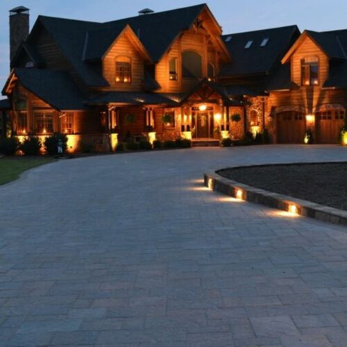 Driveway of patio pavers leading to a beautiful home with stone accents and custom lighting in the stone