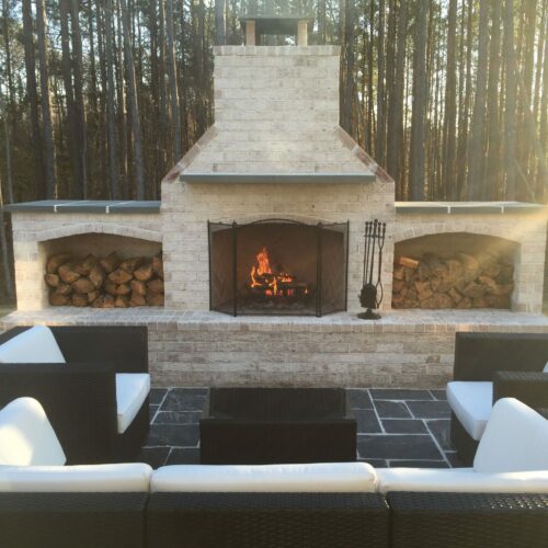 Custom Fireplace lit with wood storage on either side, backing up to the woods