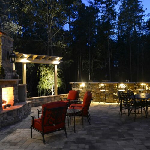 Outdoor living space with stone fireplace, retaining wall and custom patio paver