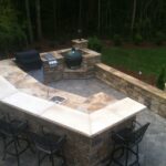Outdoor living space with outdoor kitchen, retaining wall and custom paver patio
